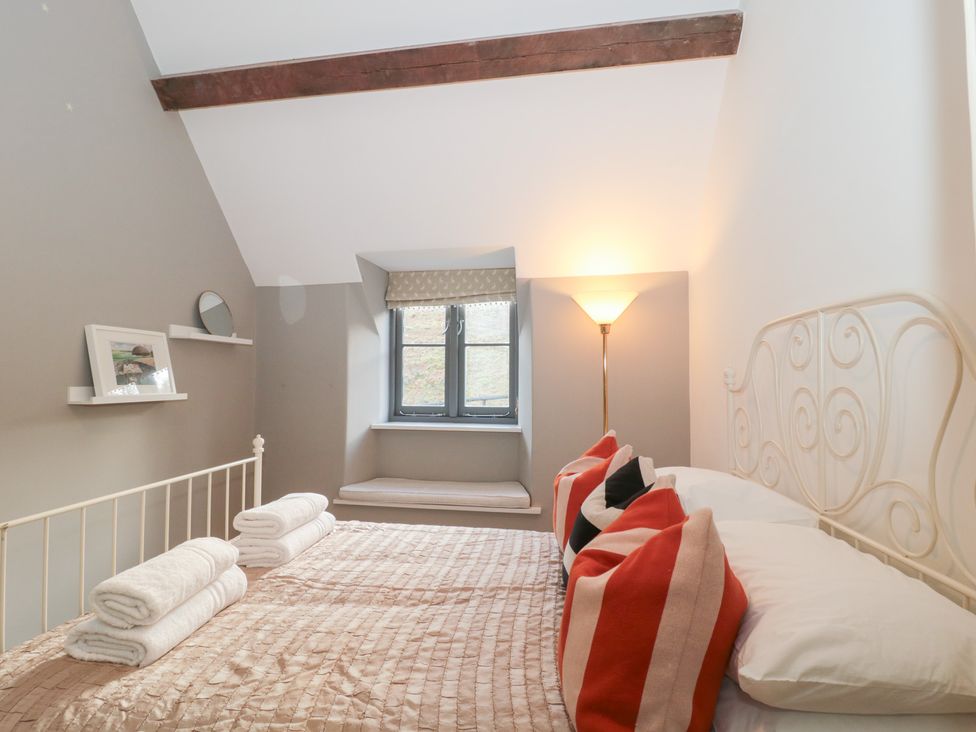 A bedroom with a bed and decorative pillows at Spring View in Kingscote, Gloucestershire
