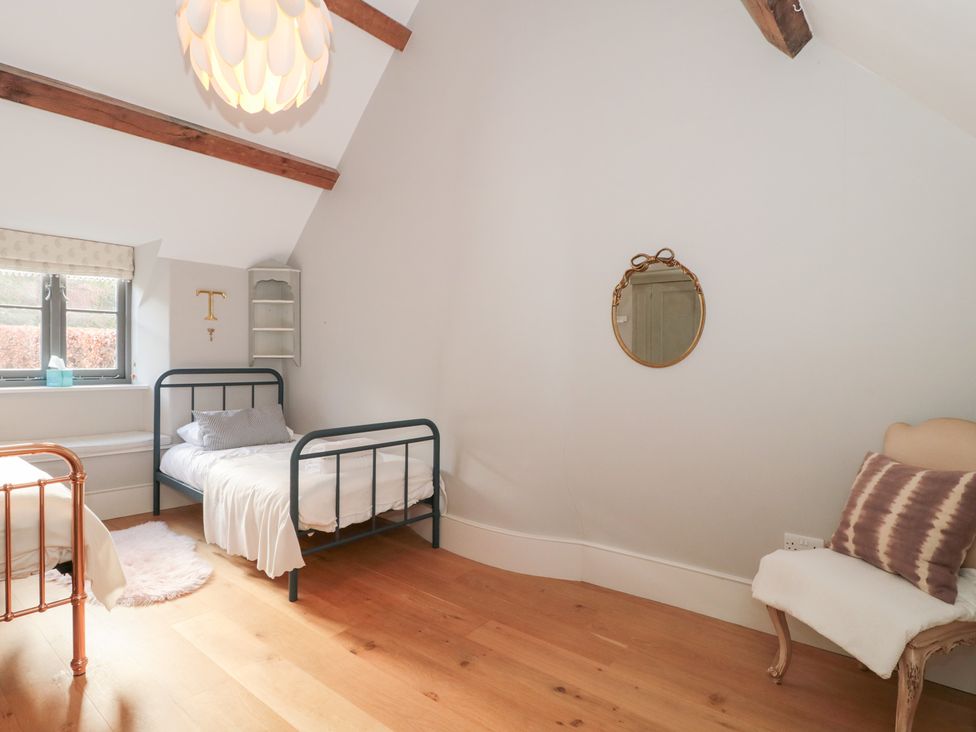 A bedroom with two beds and a mirror at Spring View, Kingscote, Gloucestershire