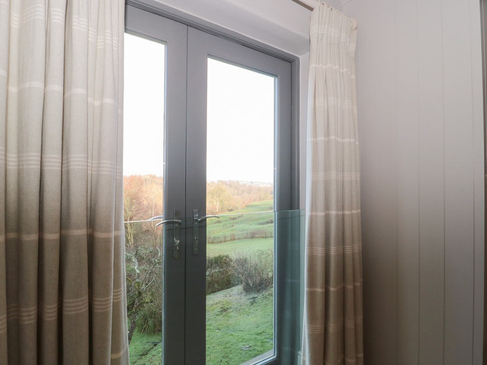 A room with glass doors and curtains at Spring View in Kingscote, Gloucestershire