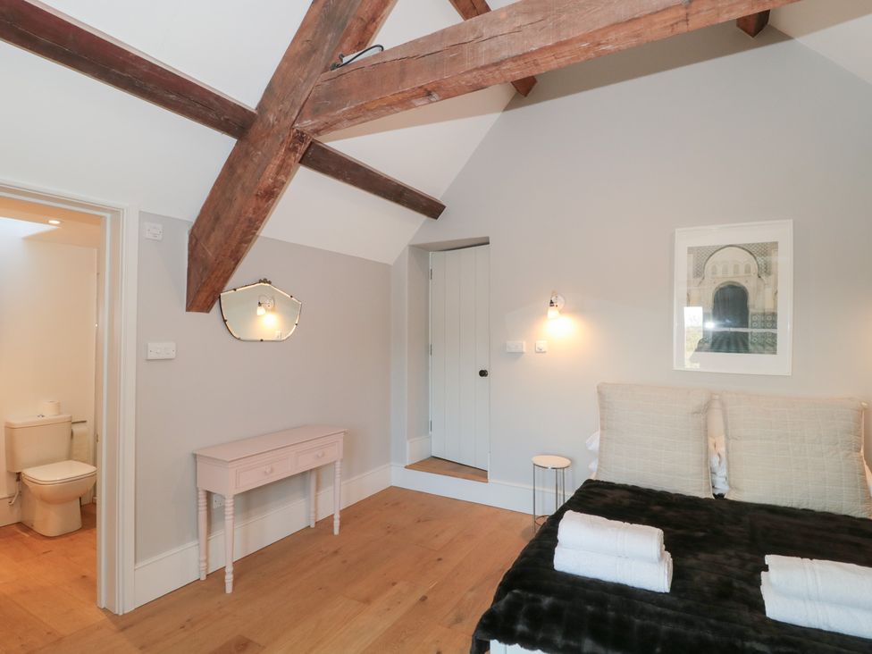 A bedroom with a bed and a bathroom door at Spring View in Kingscote, Gloucestershire