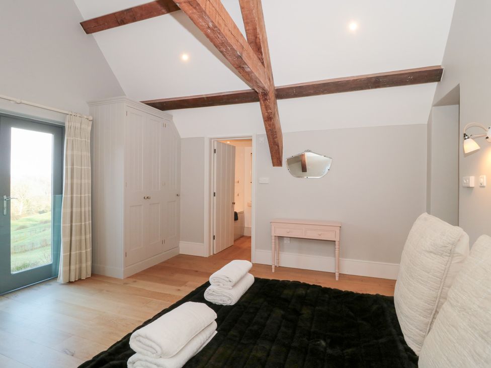 A bedroom with a bed and a wardrobe at Spring View in Kingscote, Gloucestershire