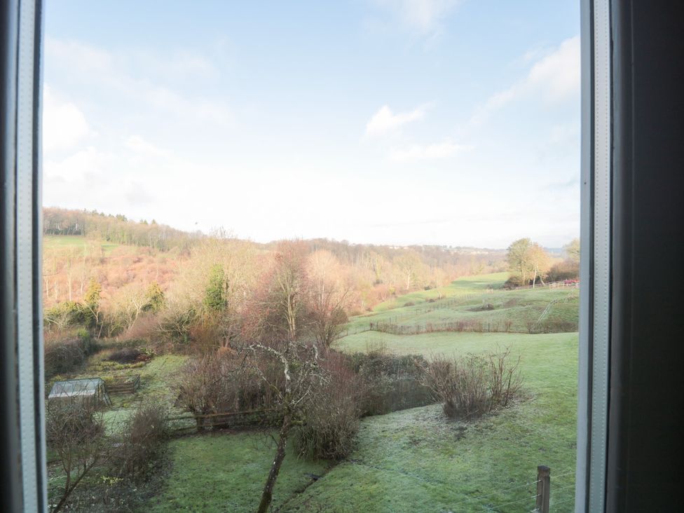 A view of a green landscape with trees from a window at Spring View, Kingscote, Gloucestershire