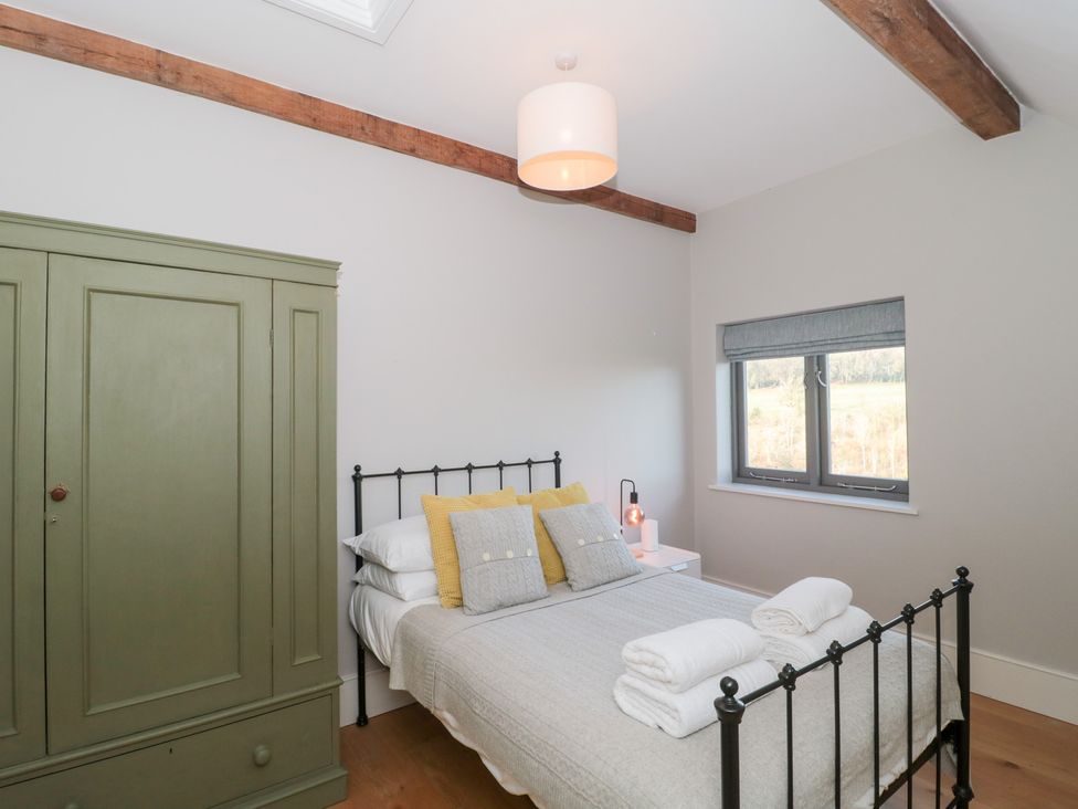 A bedroom with a bed and wardrobe at Spring View in Kingscote, Gloucestershire