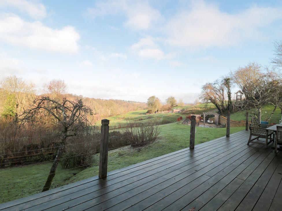 A garden view with decking and trees at Spring View, Kingscote, Gloucestershire