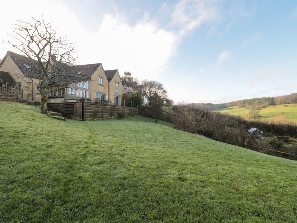 A garden with a house and trees at Spring View in Kingscote, Gloucestershire
