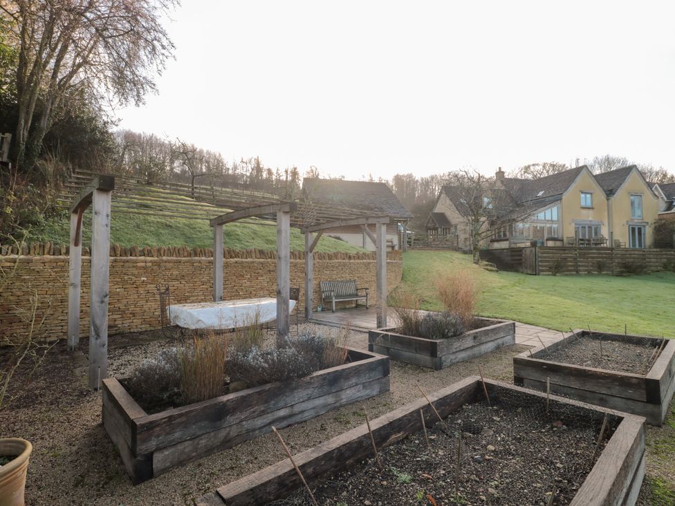 A garden with raised beds and a bench at Spring View in Kingscote, Gloucestershire