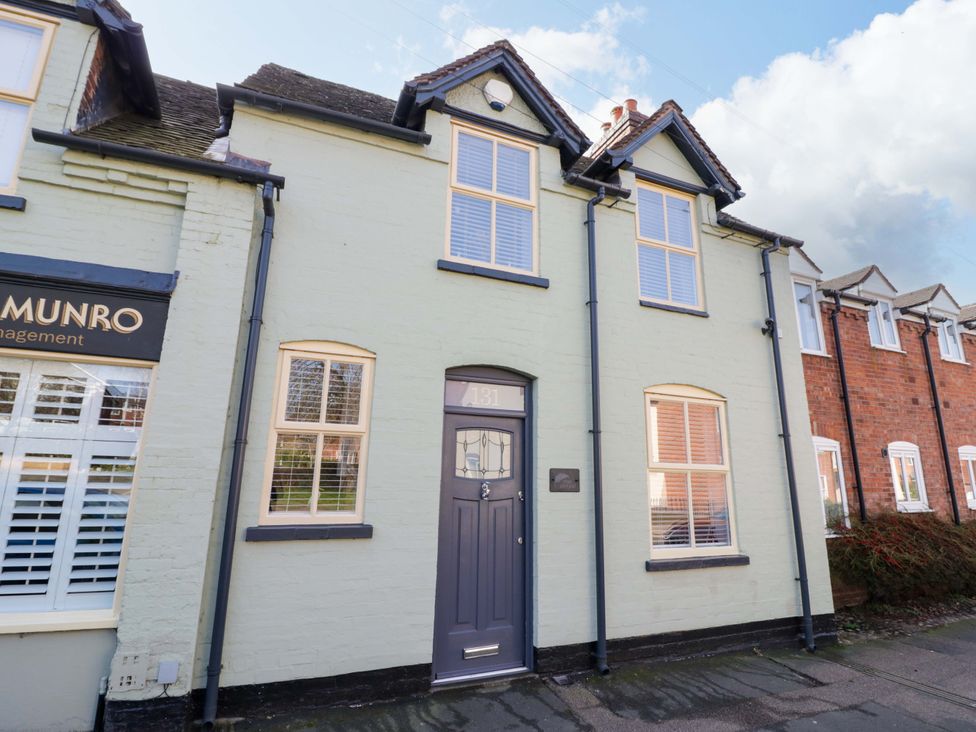 A house with a grey door and multiple windows at Fern Cottage in Lichfield