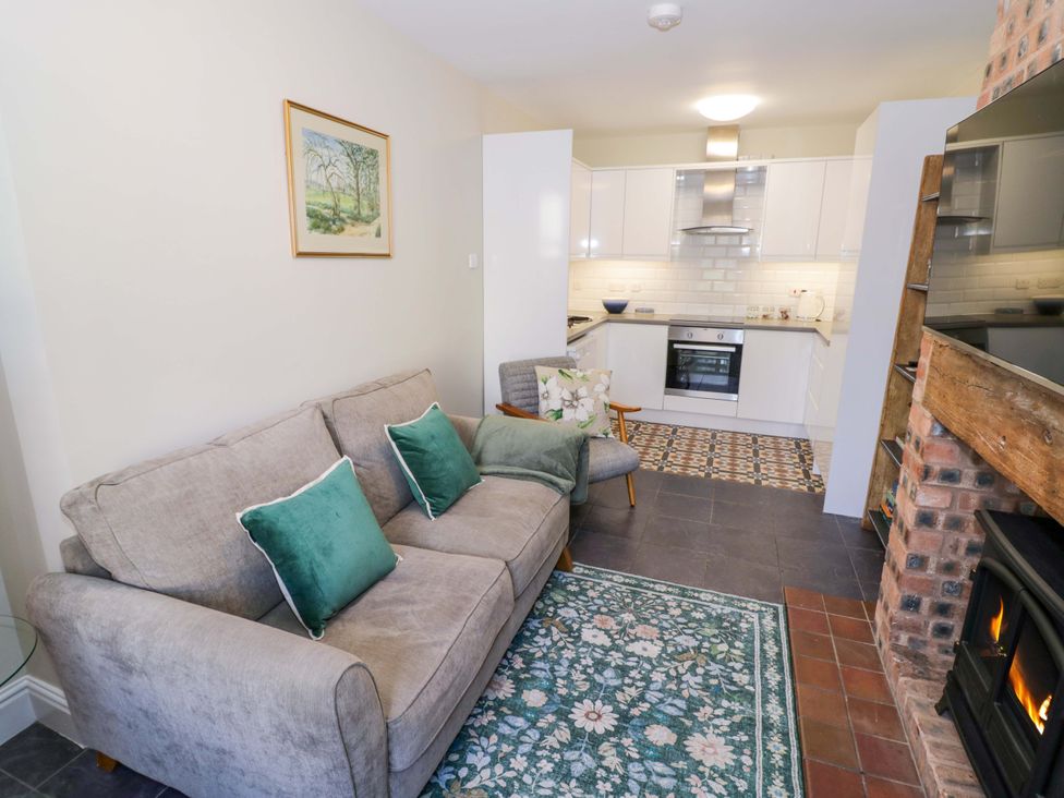 A living room featuring a sofa and kitchen area at Fern Cottage in Lichfield
