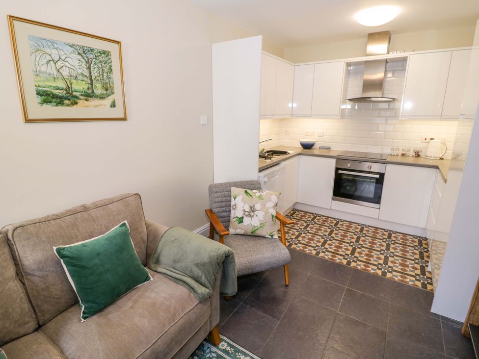 A living room with a sofa and kitchen area at Fern Cottage in Lichfield