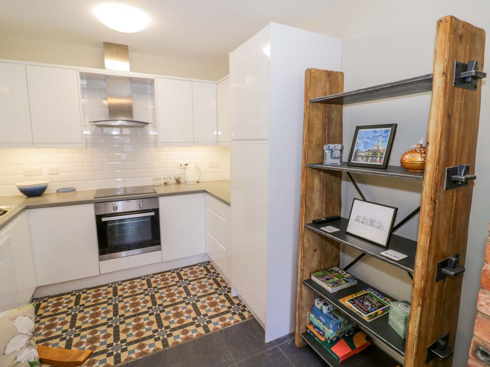 A kitchen with cabinets and an open shelf at Fern Cottage in Lichfield