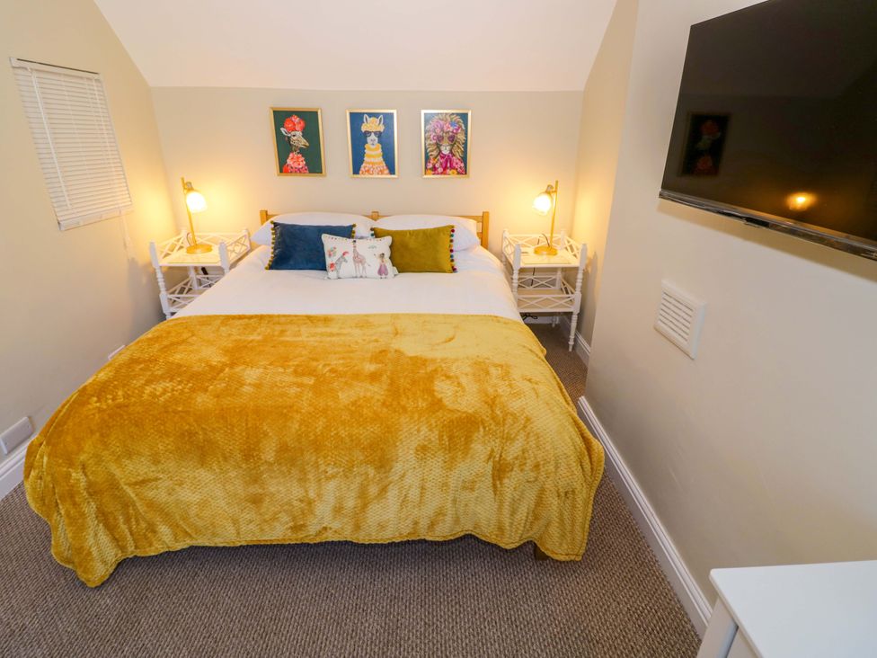 A bedroom with a bed, nightstands and wall art at Fern Cottage in Lichfield