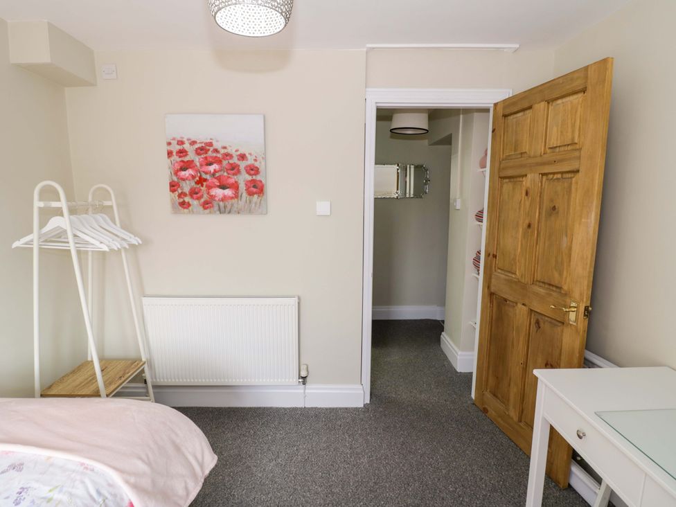 A bedroom with a coat rack and a door at Fern Cottage in Lichfield