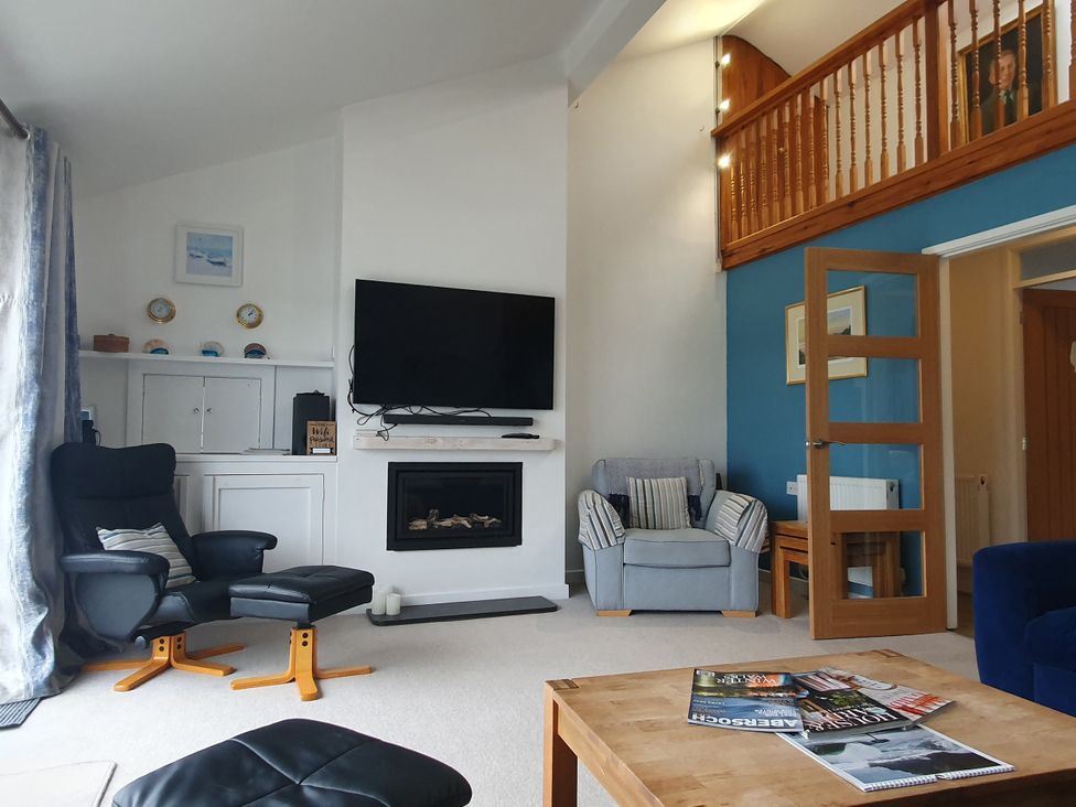 A living room with a television and fireplace at Gilfach Goed in Pwllheli