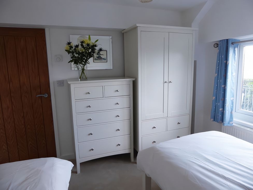 A bedroom with a dresser and wardrobe at Gilfach Goed in Pwllheli