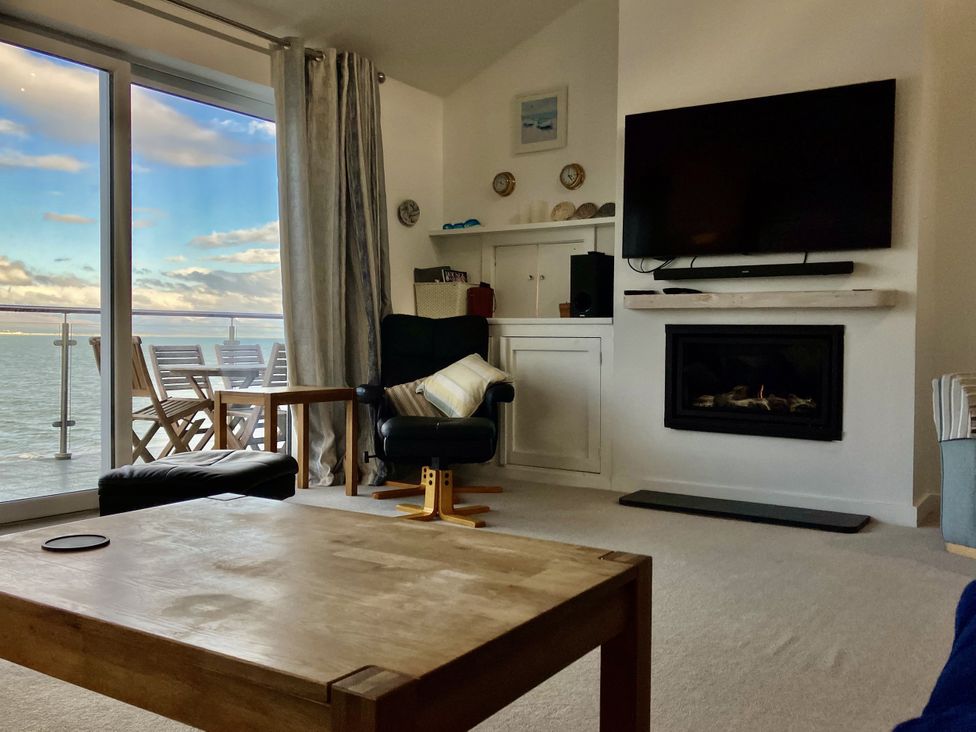 A living room with a tv, sofa, and fireplace at Gilfach Goed in Abersoch