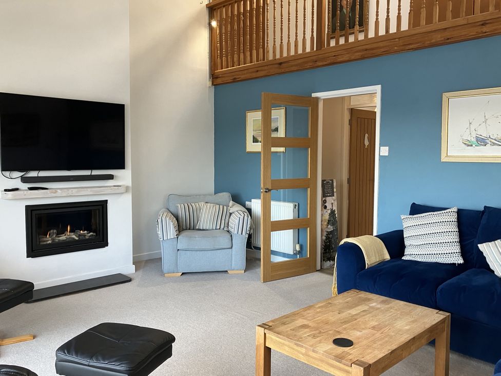 A living room with a television and fireplace at Gilfach Goed in Abersoch