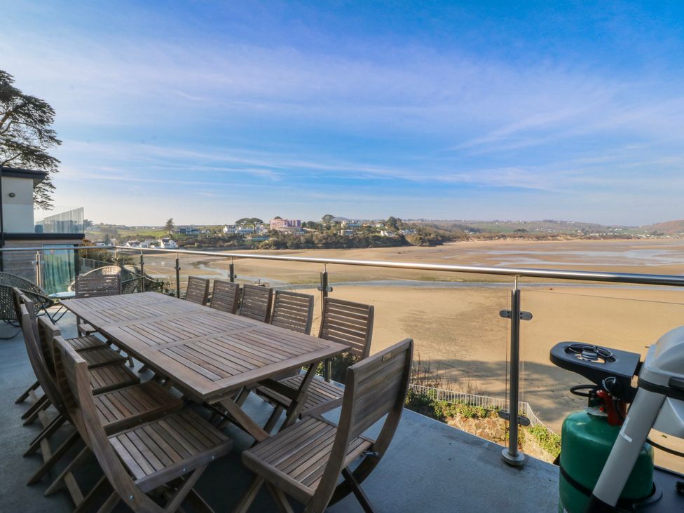 A dining area with a table and chairs on a balcony at Gilfach Goed in Abersoch