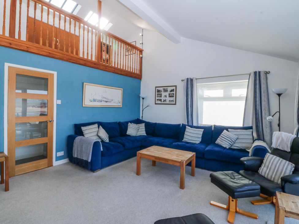 A living room with a blue sofa and wooden coffee table at Gilfach Goed in Abersoch