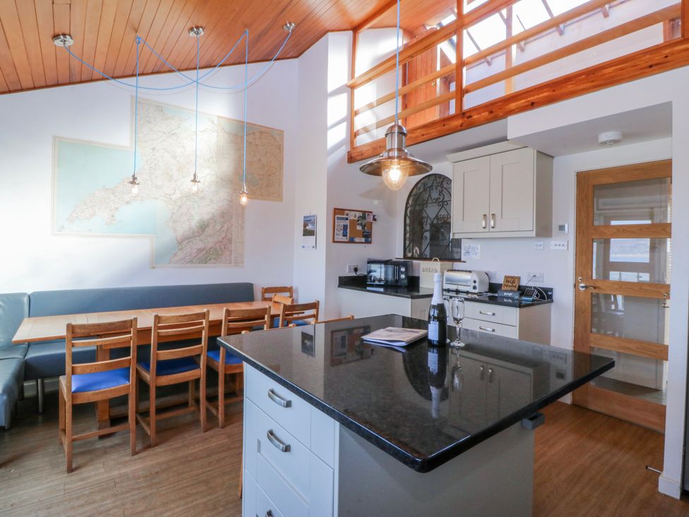 A kitchen with a table, chairs, and a map at Gilfach Goed in Abersoch