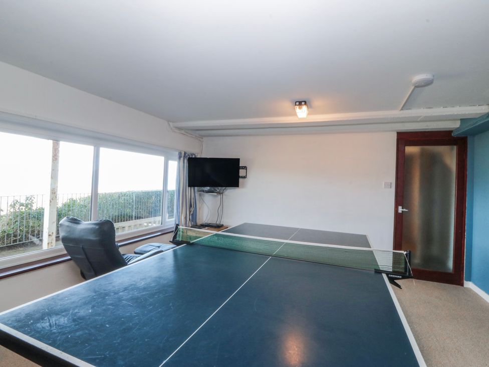 A recreation room with a ping pong table and television at Gilfach Goed in Abersoch