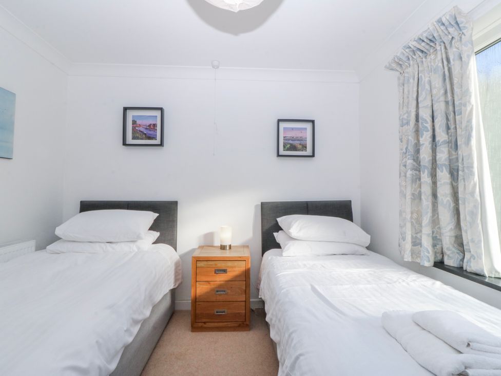 A bedroom with twin beds and bedside table at Gilfach Goed in Abersoch