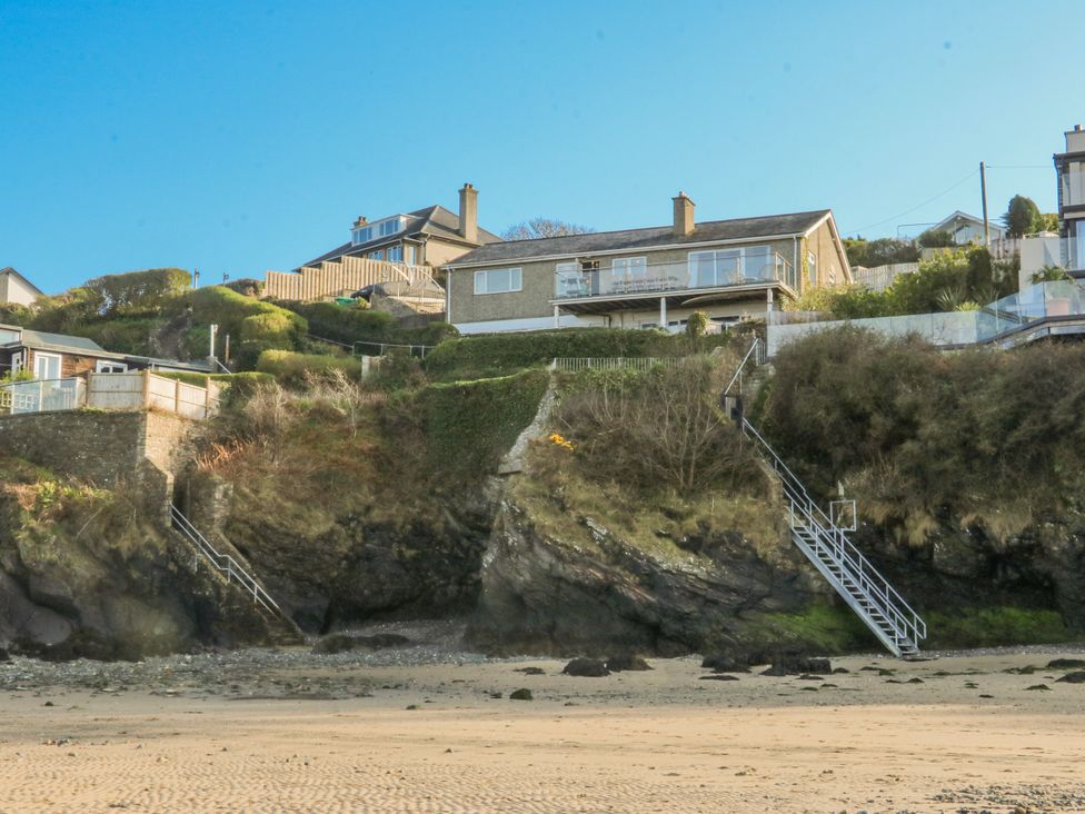 Houses on a cliff with stairs leading down to the beach at Gilfach Goed in Abersoch