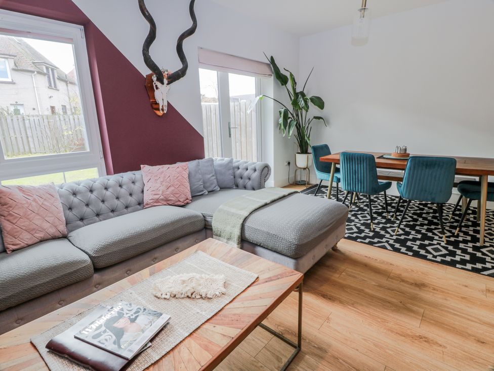 A living room with a sofa and dining area at 14 Old Market Place Bonnyrigg