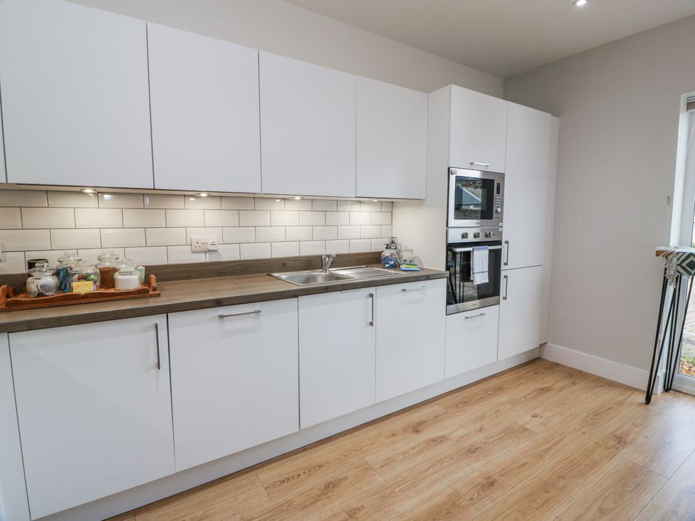 A kitchen with white cabinets and stainless steel appliances at 14 Old Market Place Bonnyrigg
