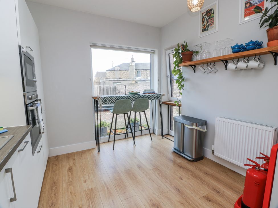 A kitchen with bar stools and a window at 14 Old Market Place Bonnyrigg