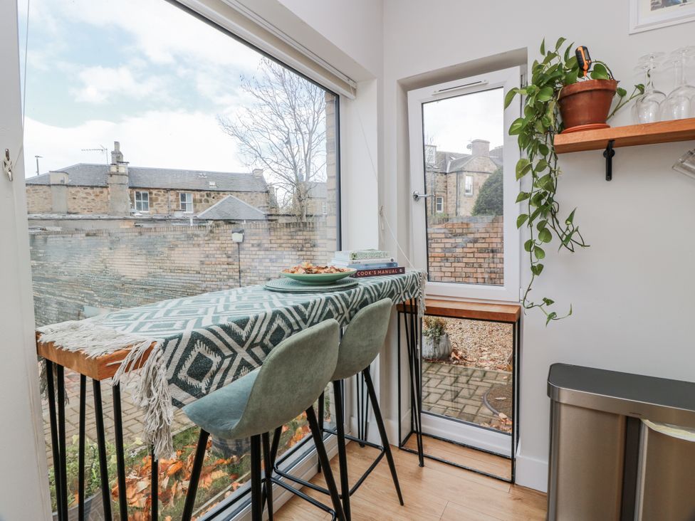 A kitchen with a table and stools next to a window at 14 Old Market Place Bonnyrigg