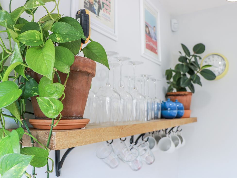 A kitchen with a wooden shelf featuring glassware and plants at 14 Old Market Place Bonnyrigg