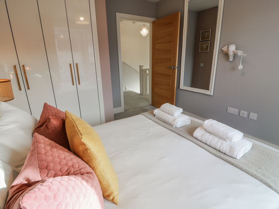 A bedroom with a bed, pillows, towels, and a mirror at 14 Old Market Place Bonnyrigg