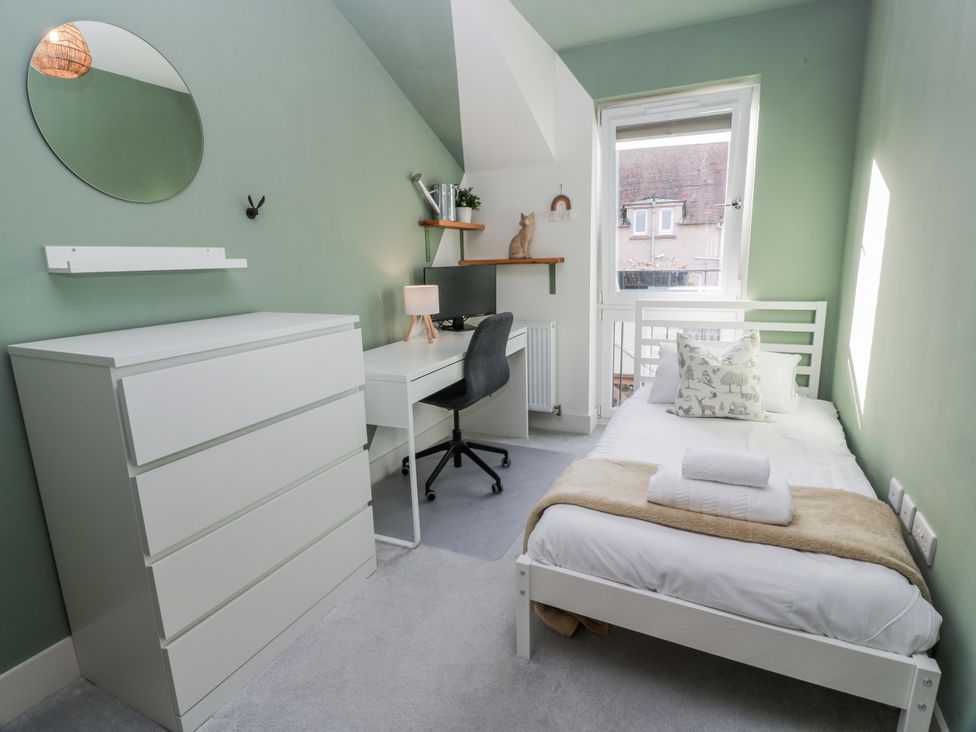 A bedroom with a bed, dresser, desk, and chair at 14 Old Market Place, Bonnyrigg