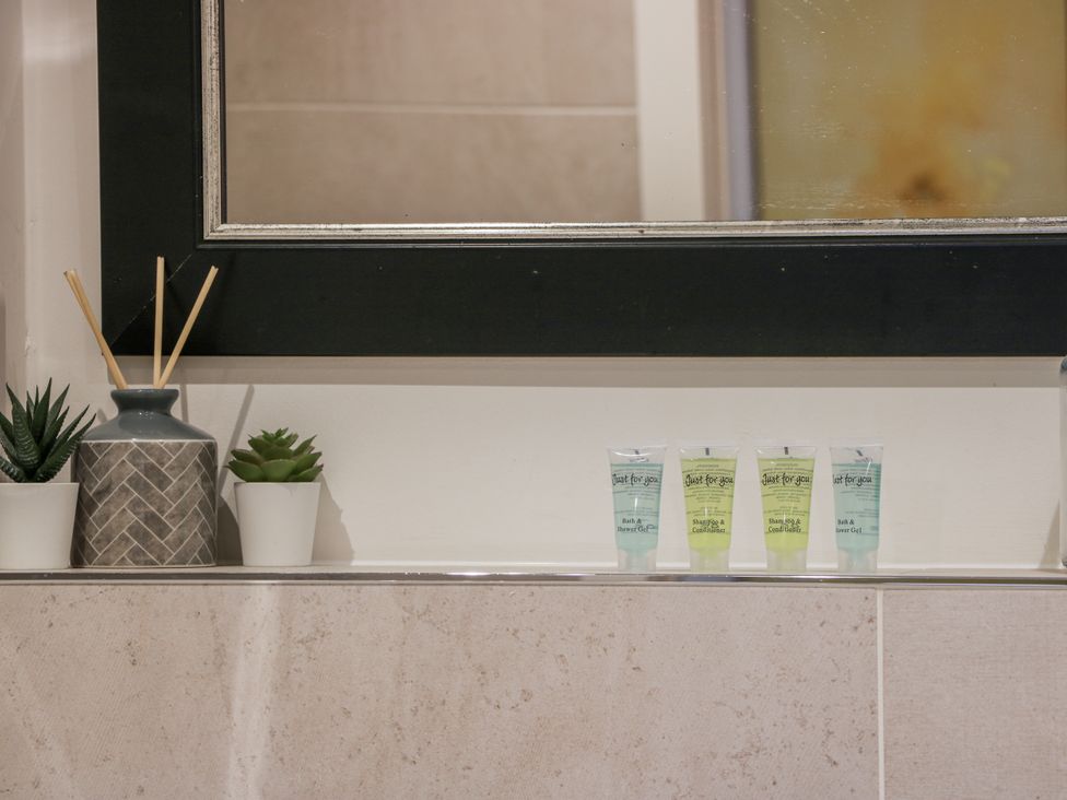 A bathroom shelf with toiletries and plants at 14 Old Market Place in Bonnyrigg