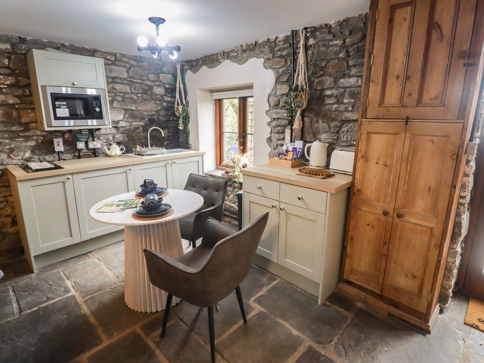 A kitchen with stone walls and wooden cabinets at Gwyn Studio in Aberdare