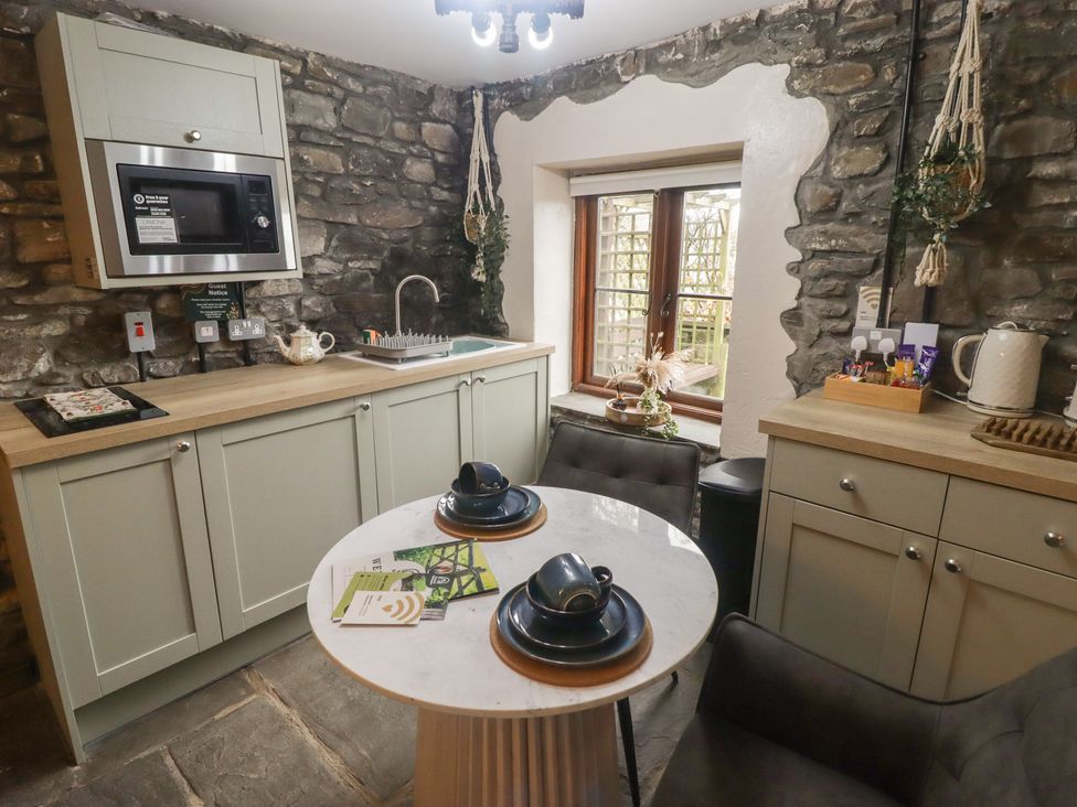 A kitchen with cabinets, a sink, and a table at Gwyn Studio in Aberdare