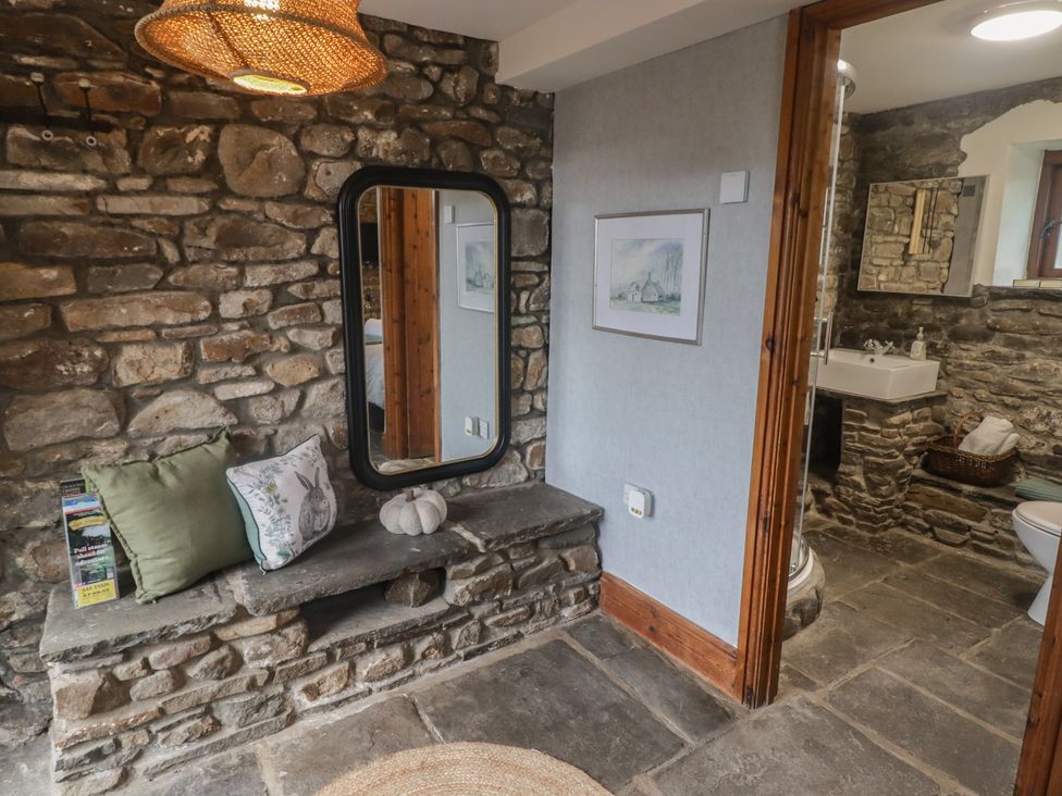 A bathroom with a mirror, bench, and a sink at Gwyn Studio in Aberdare