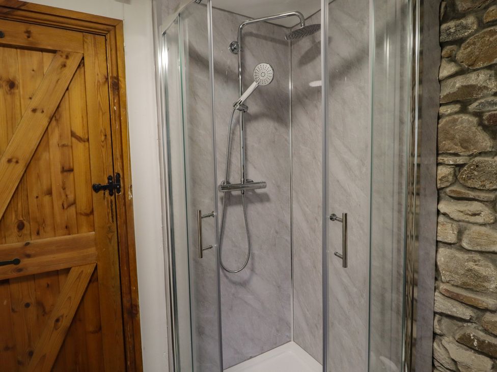 A shower with a glass enclosure and a wooden door at Gwyn Studio in Aberdare