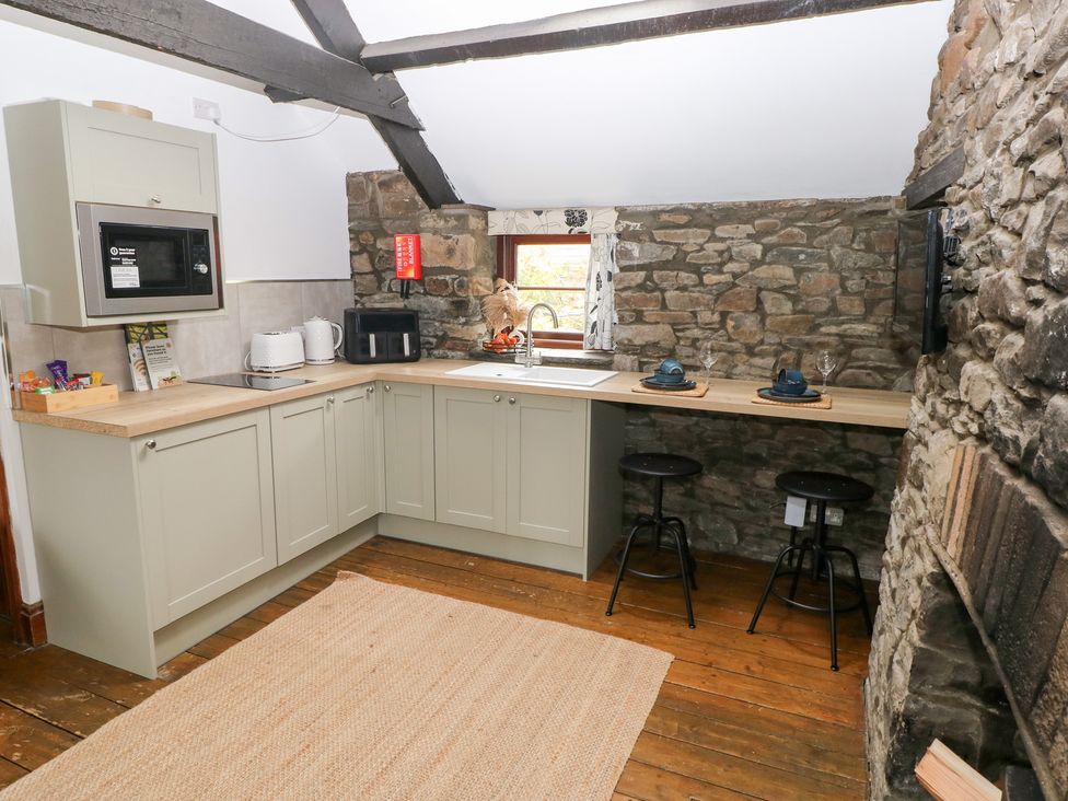 A kitchen with stone wall and bar stools at Glas Studio in Aberdare