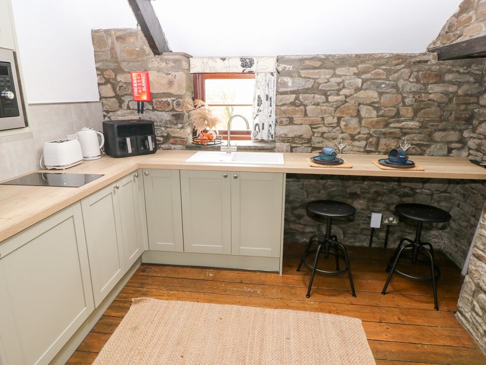 A kitchen with a sink and stools at Glas Studio in Aberdare