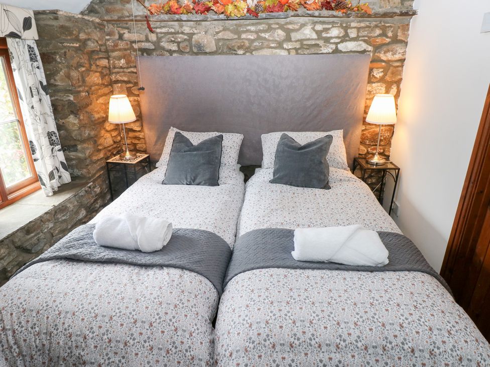 A bedroom with twin beds and stone wall at Glas Studio in Aberdare