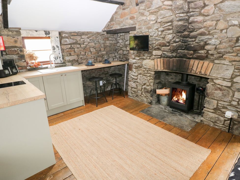 A kitchen with a fireplace and barstools at Glas Studio in Aberdare