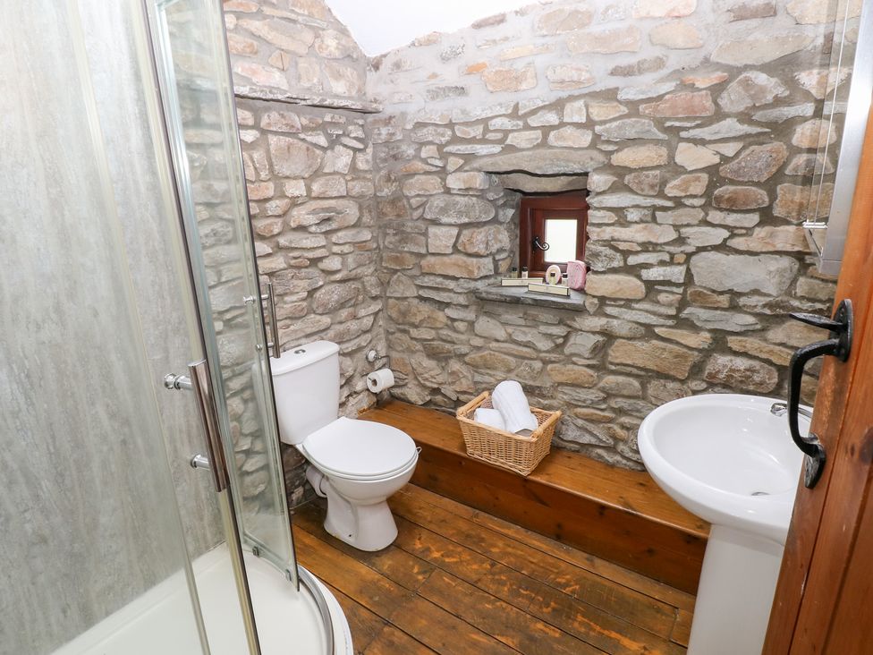 A bathroom with stone walls and wooden flooring at Glas Studio in Aberdare