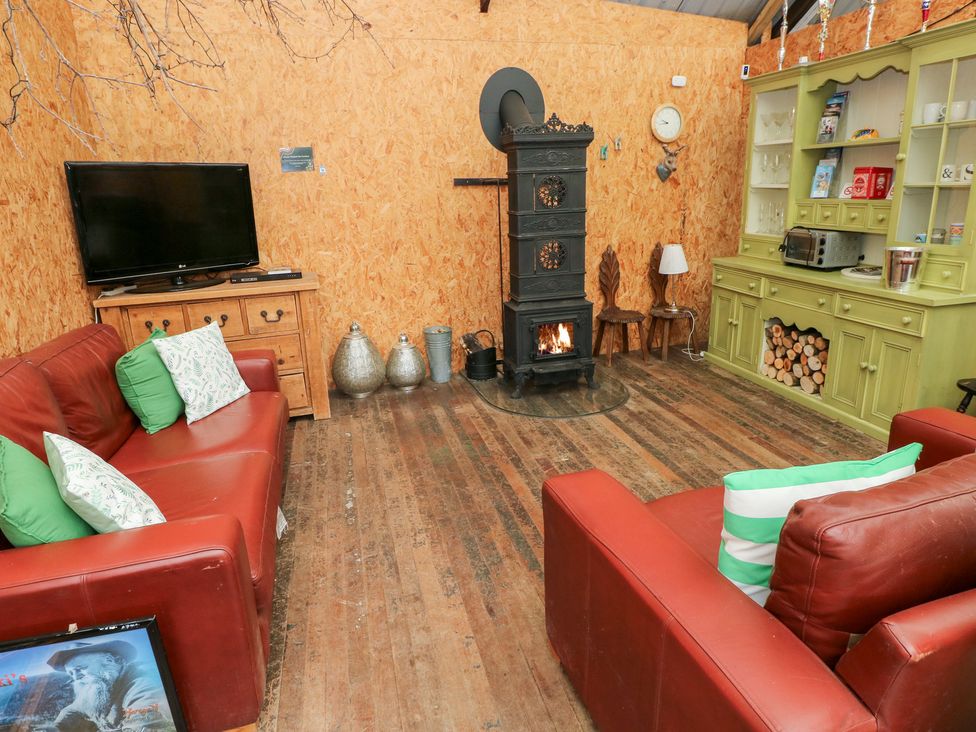 A snug with red sofas and a stove at Glas Studio in Aberdare