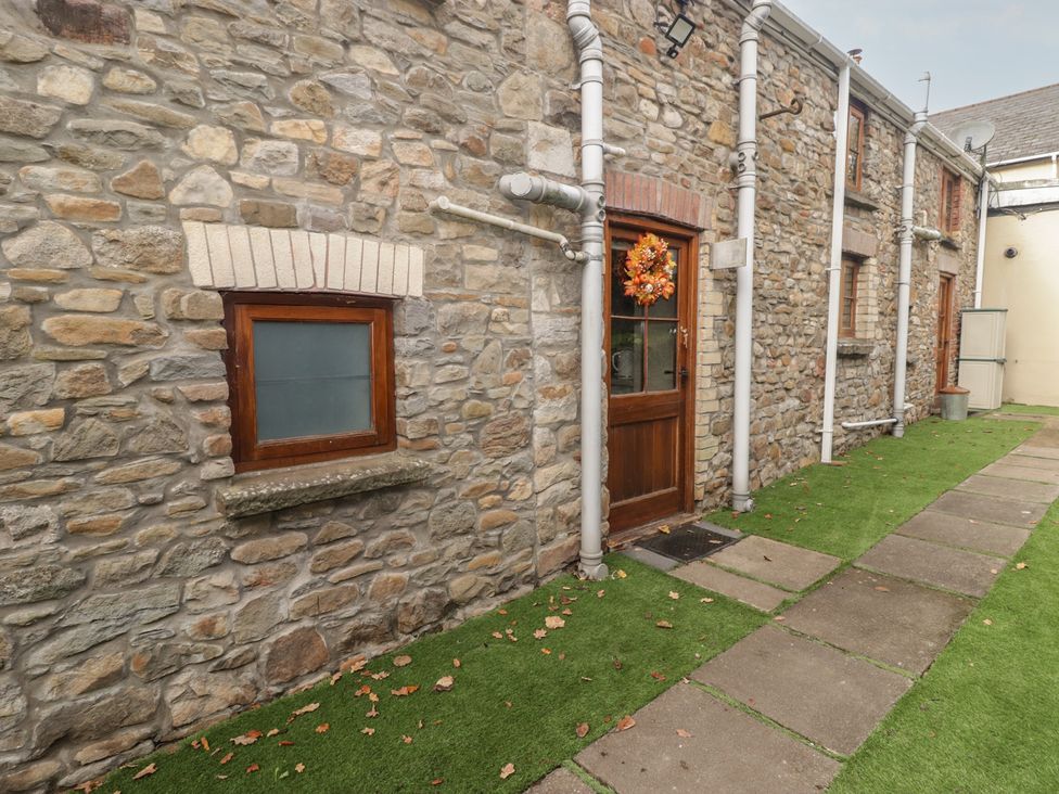 An outdoor area with stone wall, wooden door, and pathway at Arian in Aberdare