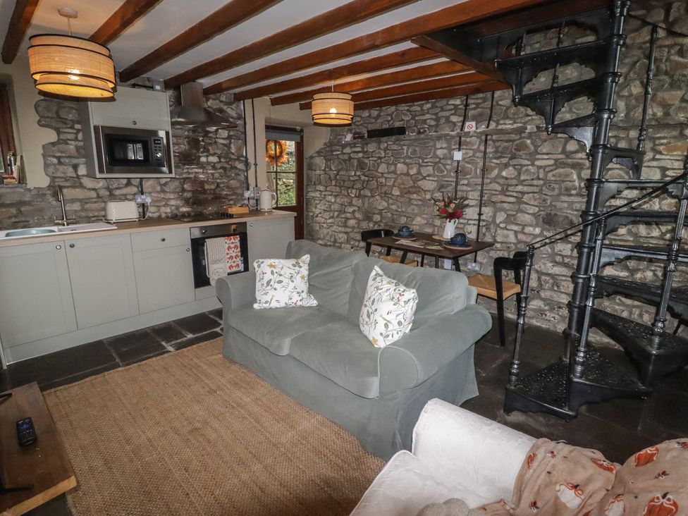 A living room with a sofa and kitchenette at Arian in Aberdare