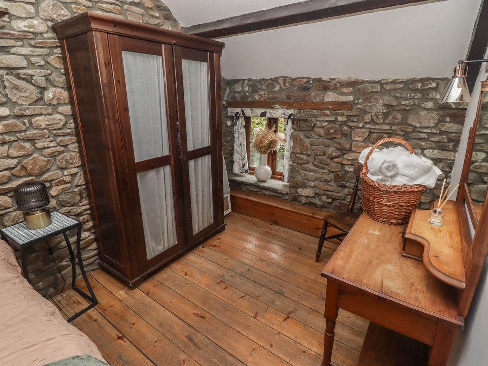 A bedroom with a wardrobe and a table at Arian in Aberdare