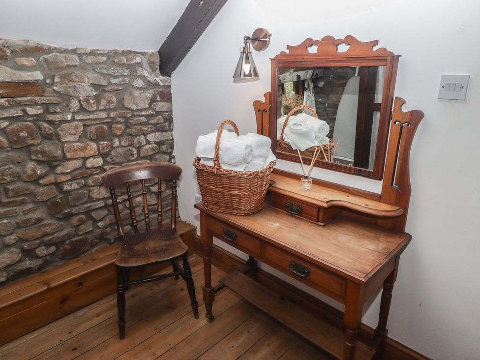 A bathroom with a vanity table, chair, basket, and towels at Arian in Aberdare