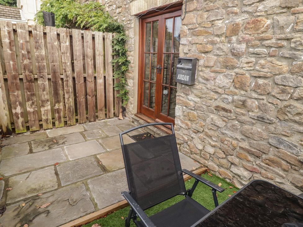 An outdoor space with a stone wall and a wooden fence at Arian in Aberdare