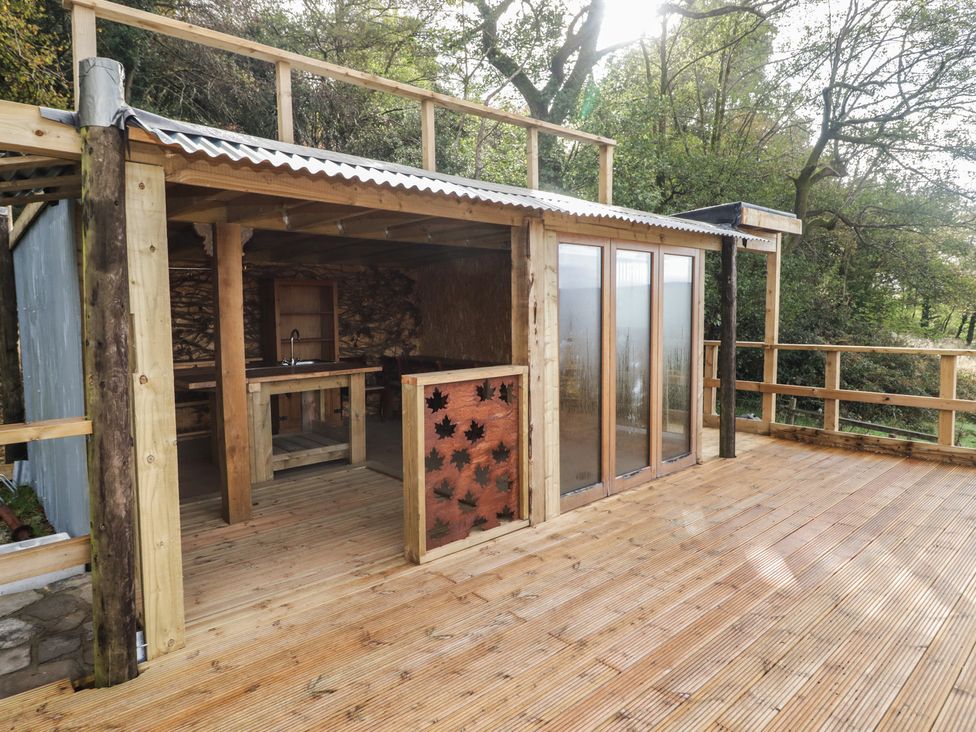 An outdoor kitchen with a wooden deck and glass doors at Arian in Aberdare